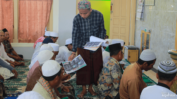 Santri Husada (berdiri) sedang membagi - bagikan pamflet tentang etika batuk, bersalaman, dan cara mencuci tangan yang baik dan benar